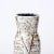 This Mid-Century Modernist White and Earth Toned Ceramic Vase With Leaf Motif is a beautiful example of Post War European...