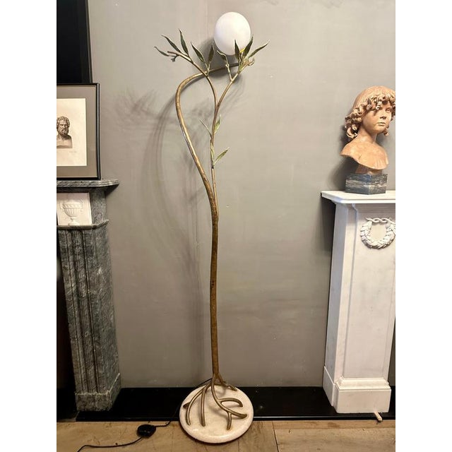 A large and very tall, wrought iron and painted floor lamp in foliate manner with white sphere lamp shade on a pivotable...