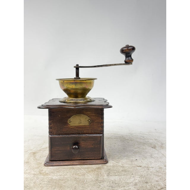 Charming coffee grinder with a solid wood body and brass top hopper. Perfect for display or as a collector's item.