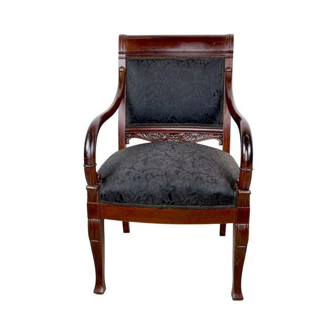 Commanding and deeply elegant, this antique Empire style armchair is a statement piece for the ages. The rich dark...