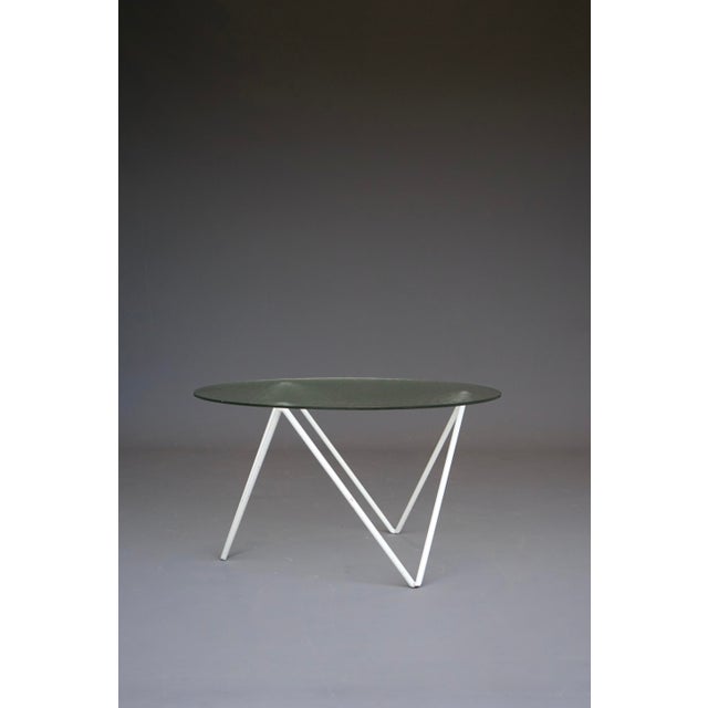 An elegant mid-century table. It has its original textured glass top and shaped painted metal base.