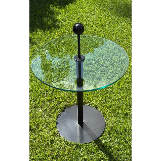 Striking vintage Italian side table by Flyline, featuring a round clear glass top supported by a sleek black cylindrical...