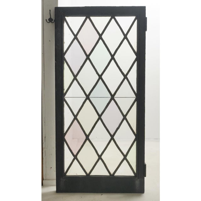Tudor style casement stained glass window with a leaded diamond pattern in a pastel color scheme. The frame is made of...