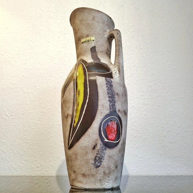 A tall, SCHEURICH KERAMIK pitcher vase from the 1950s with an abstract fruit motif in yellow, red, turquoise, and black on...