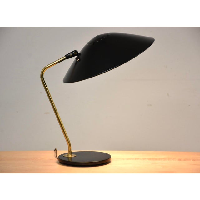 A mid century modern black enamel and brass table lamp designed by Gerald Thurston for Lightolier. Professionally...
