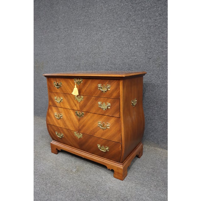 Weiman cherry Bombay commode featuring a shaped front, four drawers, brass hardware, and beautiful cherry veneer detail.