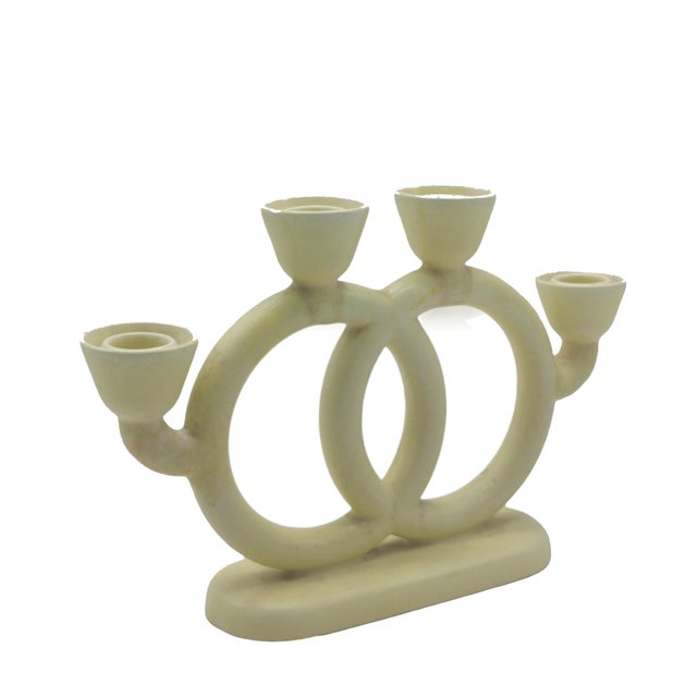 Ivory-colored glazed ceramic candelabrum with four lights and an elliptical base with rounded corners, surmounted by two...