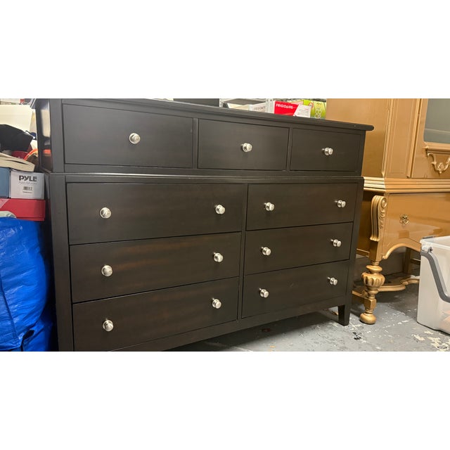 Black wooden dresser featuring eight spacious drawers with silver knob hardware. Simple, clean silhouette that works well...