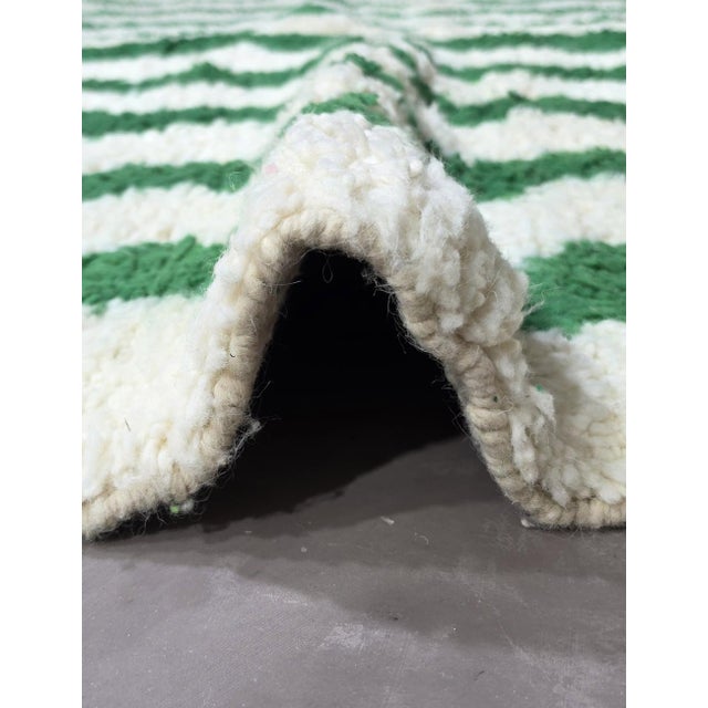 Contemporary Moroccan Rug | Handwoven Berber Wool Rug with Ivory Field and Green Wave Stripes This crisp contemporary rug...