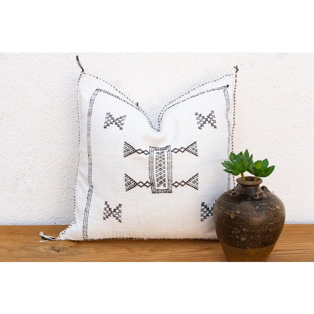 A stitched border frames the entire face of this handcrafted Moroccan cactus silk pillow, centered on a bowtie medallion...