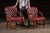Elegant pair of round-backed dining chairs upholstered in richly toned burgundy leather with deep button tufting and brass...