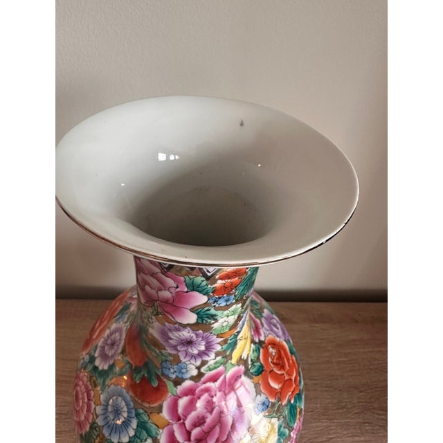 A striking vintage Chinese porcelain vase in the Famille Rose style, richly decorated with an exuberant allover botanical...