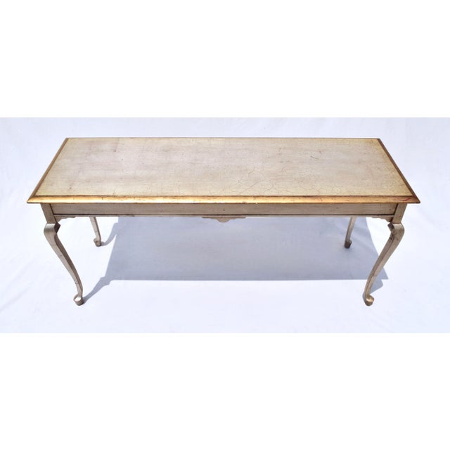An antiqued silver & gold console table with elegant lines of generous dimensions suitable for a variety of uses. A...