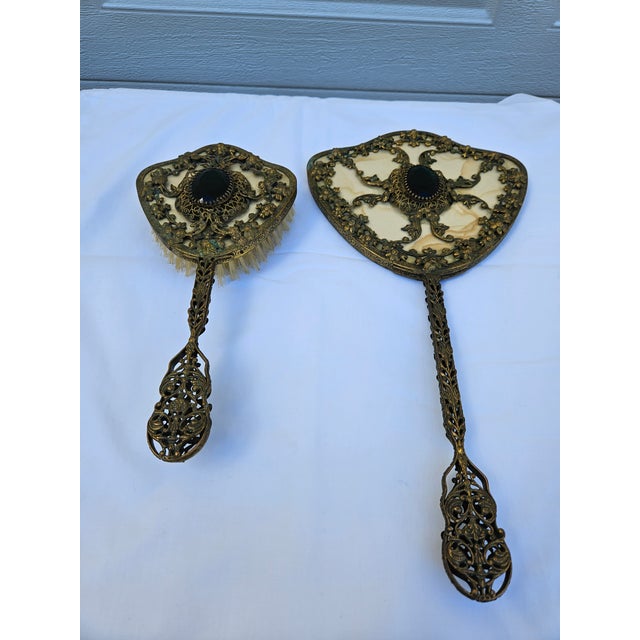A beautiful brass filigree vanity mirror and brush set with jeweled (cut glass) center pieces. The cut glass is an...