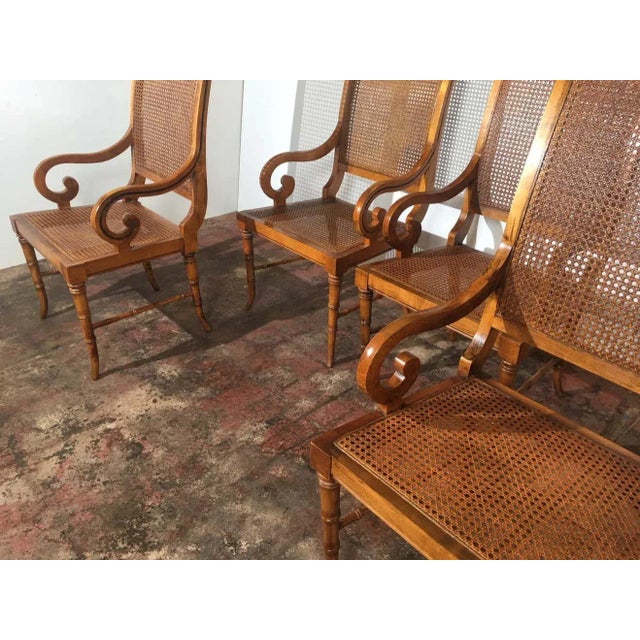 Set of four cane seat cane back dining room chairs. The arms are curved and the legs are faux bamboo. Measure arm: 23.50"H.