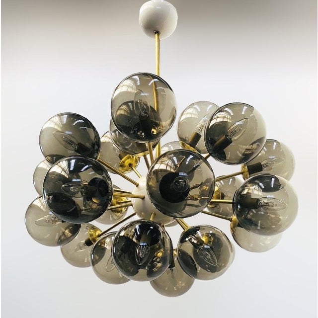 Italian oval shaped sputnik chandelier with 24 smoky Murano glass globes mounted on brass frame in unlacquered natural...