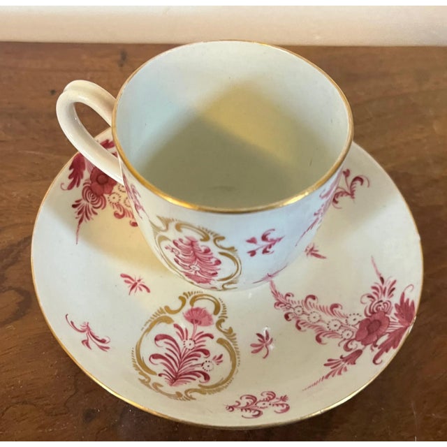 Antique 18th century German porcelain cup and saucer. Decorated with puce flowers enhanced by rich gilding. Saucer...