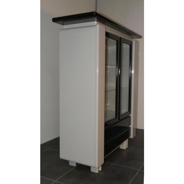 Two-tone lacquered wood cabinet in black and pearl gray, with glass front panels and lower drawers. Made in the 1980s,...