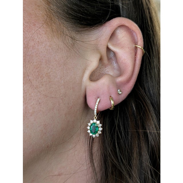 A true celebration of color and light, these earrings feature vivid oval Zambian emeralds surrounded by a starburst of...