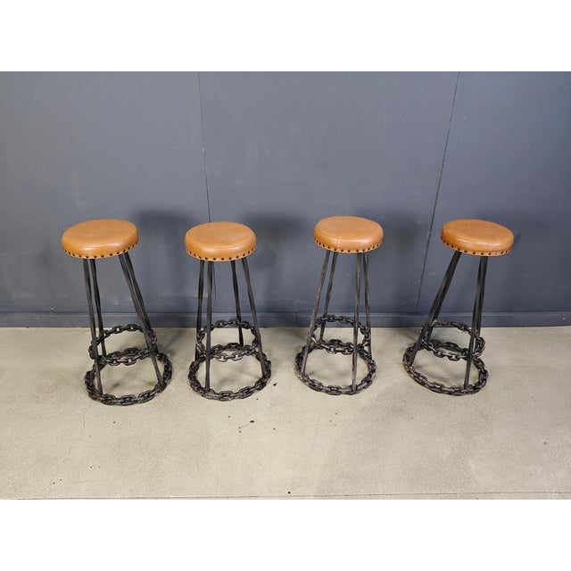 Very cool brutalist bar stools made from twisted wrought iron and chain links finished with brown leather seats. Needless...