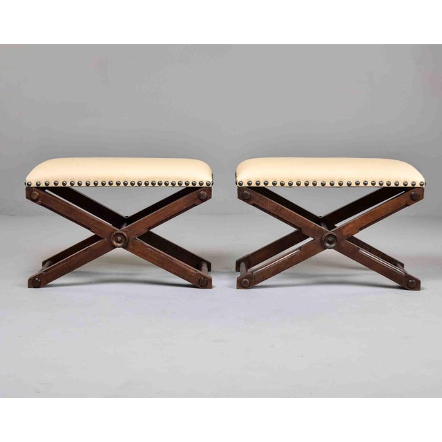 Found in France, this pair of curule-form stools dates to circa 1910. Dark hardwood frames feature bold X-form bases with...
