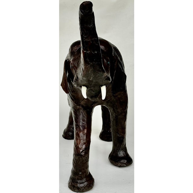 Vintage leather elephant sculpture, 24" high, in richly patinated dark brown leather with raised trunk for good fortune. A...