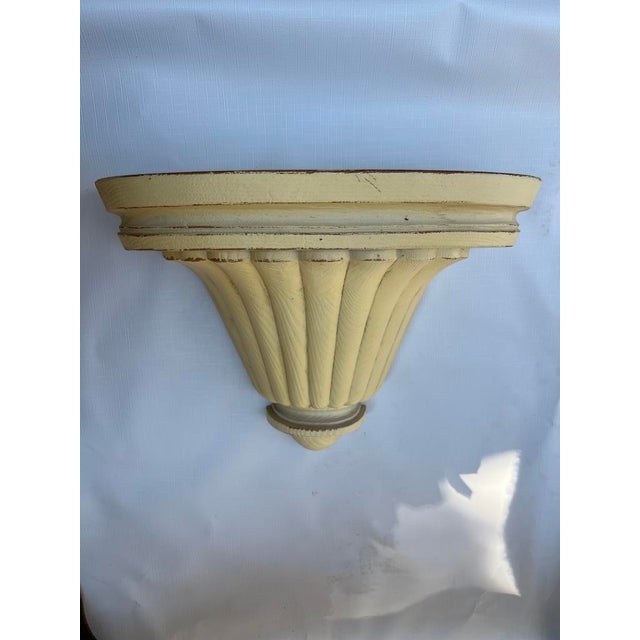 A single vintage curved faux wood wall bracket or shelf featuring a faux wood grain finish.