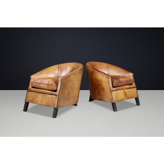 Bold Dutch armchairs with sculptural lines and beautifully aged cognac leather patina. A powerful and characterful set of...