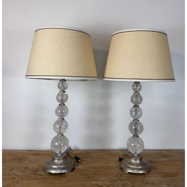 A sublime and highly coveted pair of vintage Hollywood Regency table lamps composed of stacked graduated rock crystal...