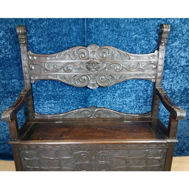 Solid wood storage bench in the Italian Renaissance style, decorated with grimacing masks. Features Gothic-style...