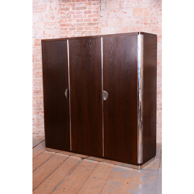 This elegant three-door wardrobe is a representative piece from the renowned manufacturer Vichr a spol. in Lysá nad Labem,...