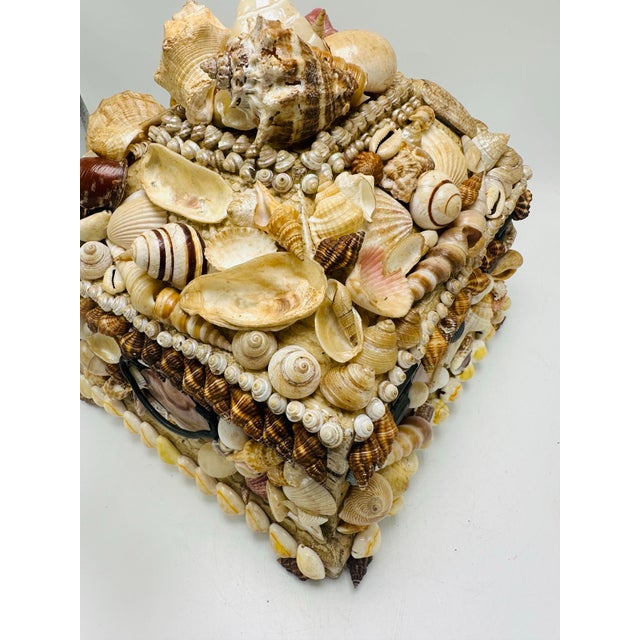 This is a decorative shell-encrusted box, a coastal folk-art style piece. The wooden box is completely covered in an...