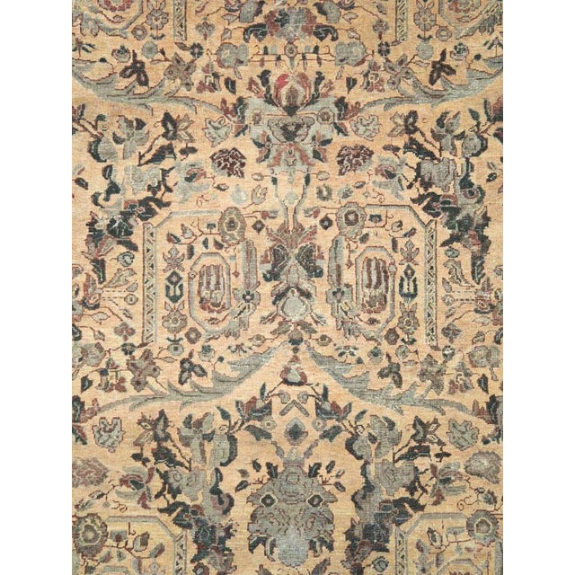 This early 20th-century Persian Mahal carpet presents a richly detailed allover floral composition across a warm ivory and...