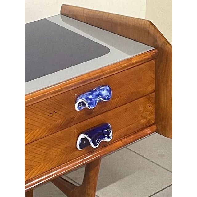 Small 1950s oak chest of drawers with decorated white and blue ceramic handles. The blue glass top with white trim is...