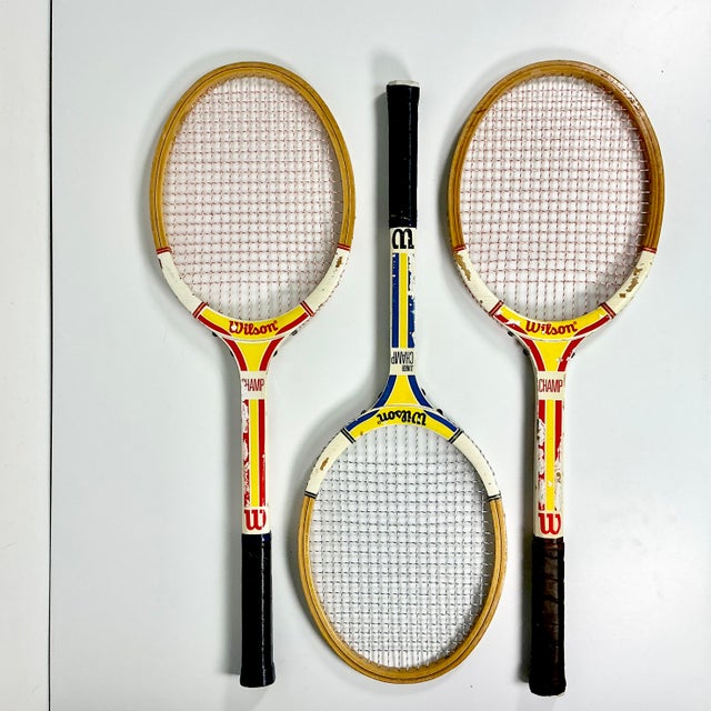 This is a set of three Vintage Wilson Wood Tennis Rackets from the 1970-1980s. Two are yellow and red paint with the third...