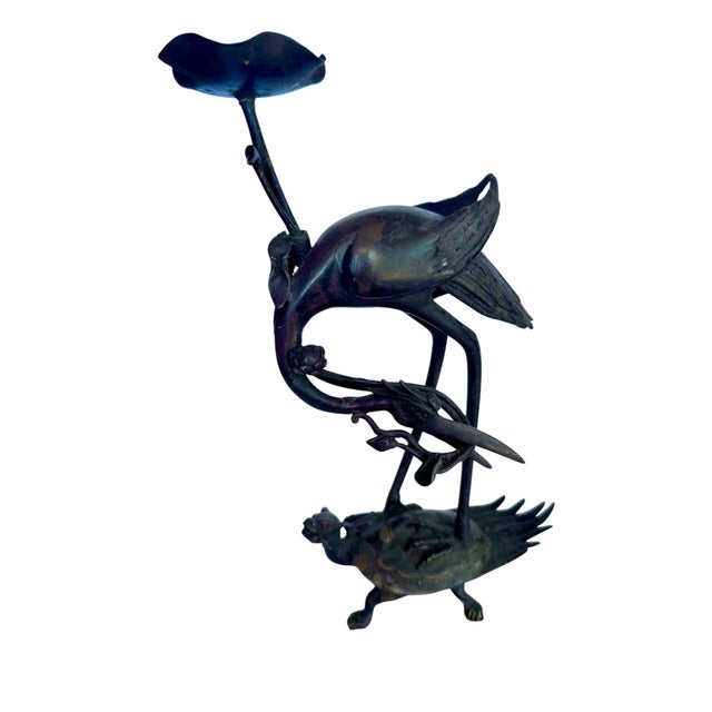 pair of antique Japanese Meiji period bronze candle holders, intricately modeled as cranes gracefully perched on the back...