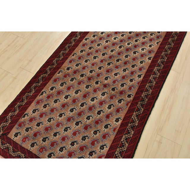 An authentic vintage tribal Baloch rug hand-knotted with fine wool and natural dyes. This nomadic oriental rug features an...