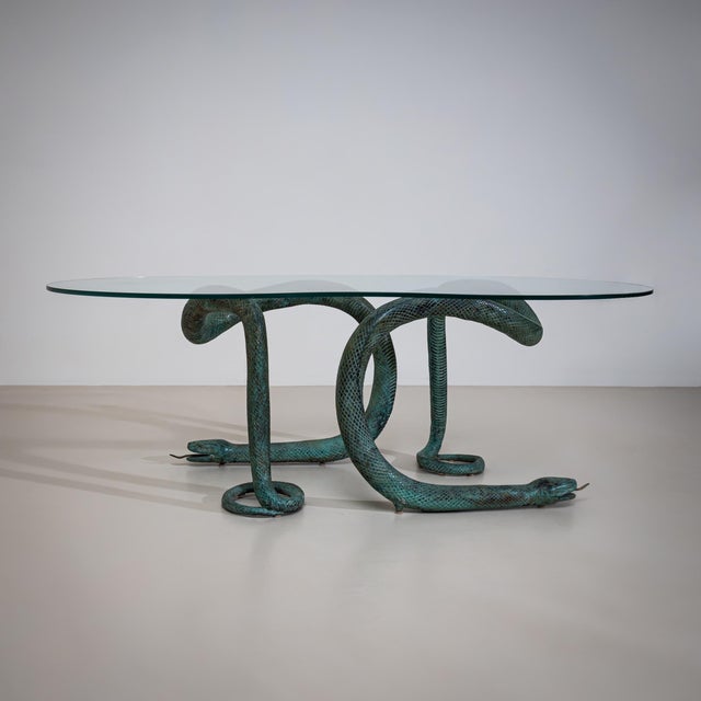 Coffee table with a kidney-shaped clear glass top. The legs are formed as intertwined, naturalistically rendered snakes...