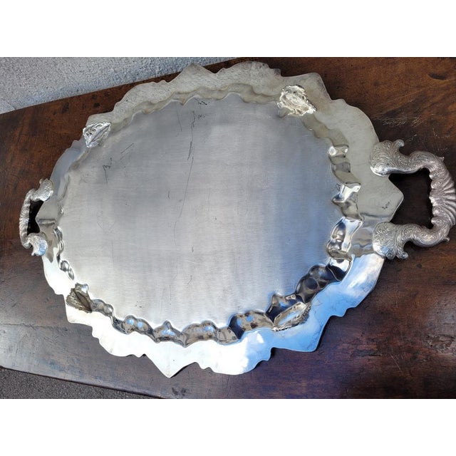Oval-shaped silver metal tray, on feet and with handles, with floral decoration Traces of use and light dents 20th century...