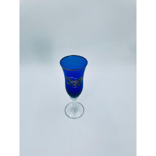 A vintage-style souvenir champagne flute, crafted from high-quality glass. The glass features a deep cobalt bowl decorated...
