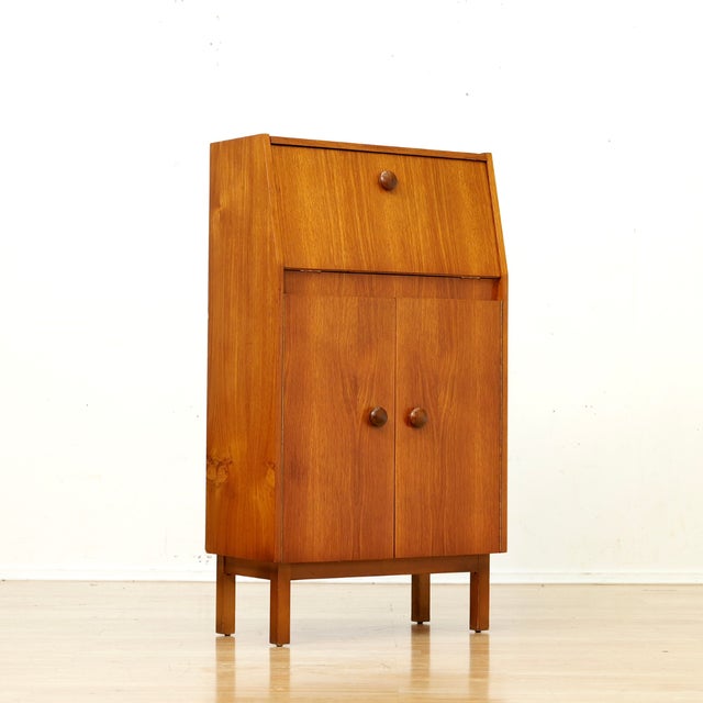 This fabulous mid century bar cabinet was made in England during the 1960s. Produced in teak, the top cabinet doors open...