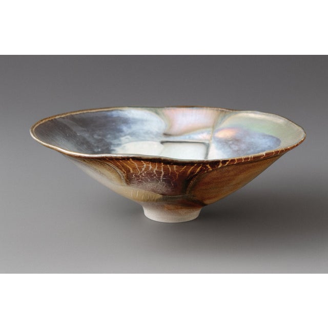A signed iridescent stretch glass bowl by Robert Coleman, dated 1989. Radiant colors shift across the shallow oval body,...