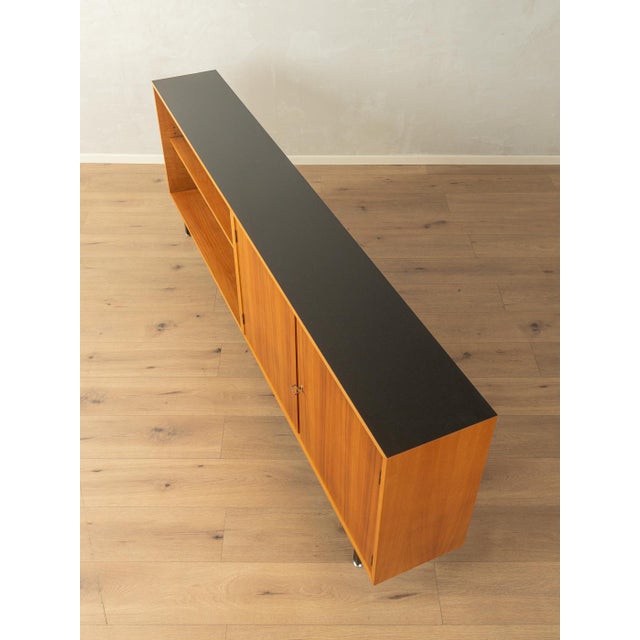 A wonderful sideboard from the 1960s. The body is finished in walnut veneer with two doors, two shelves, and new square...