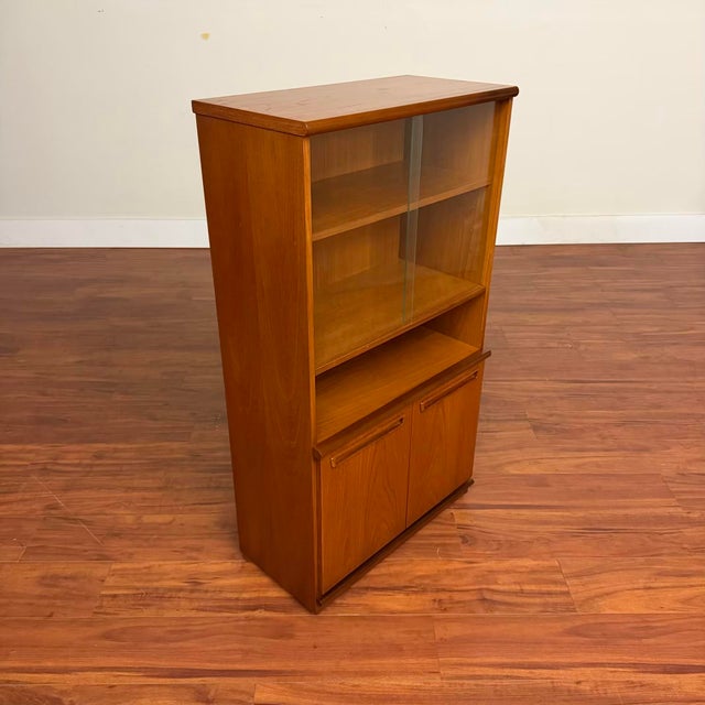 Vintage small teak display cabinet made in the U.K. by Meredew circa 1970's. It features upper sliding glass doors opening...