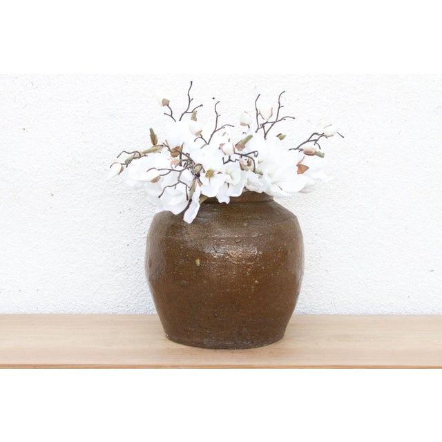 This antique glazed pot is a testament to the elegant simplicity of utilitarian design. Likely originating from Asian...