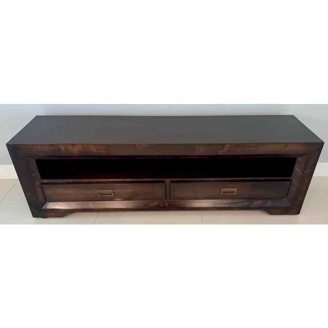 Chunky framed rectangular frame design, a dark tobacco stained finish, a wide open media shelf, and two bottom storage...