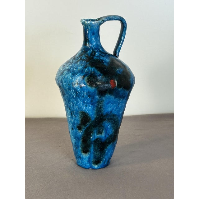 Jug-shaped vase in majolica and glazed terracotta with abstract polychrome red and black motifs on a blue background,...
