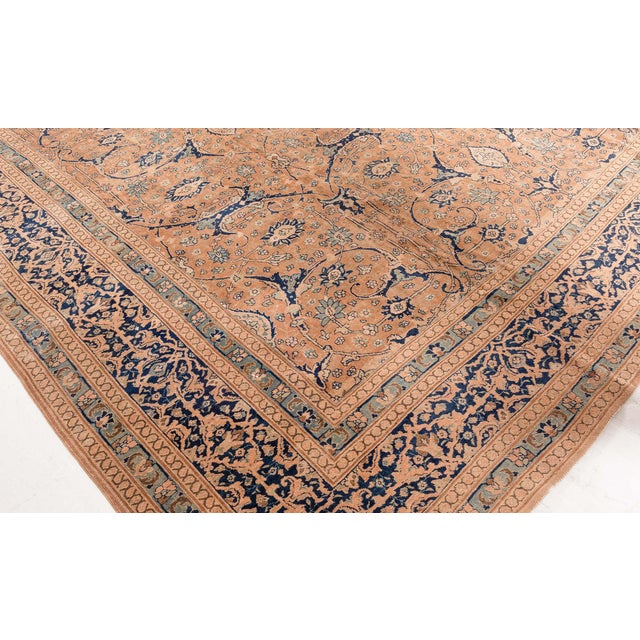 A Persian Tabriz rug having a camel field with a curvilinear trellis overall of split-leaf and palmette vinery and...