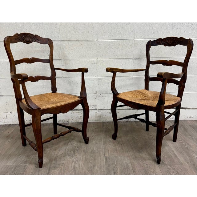 This is a gorgeous pair of antique French Country / Louis XV–style ladder back rush seat armchairs crafted in solid oak,...