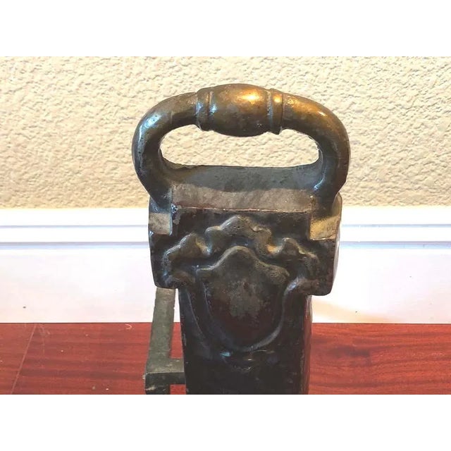 A sturdy pair of andirons, no frills and cabin worthy work horses. They are solid cast iron with what appears to be brass...